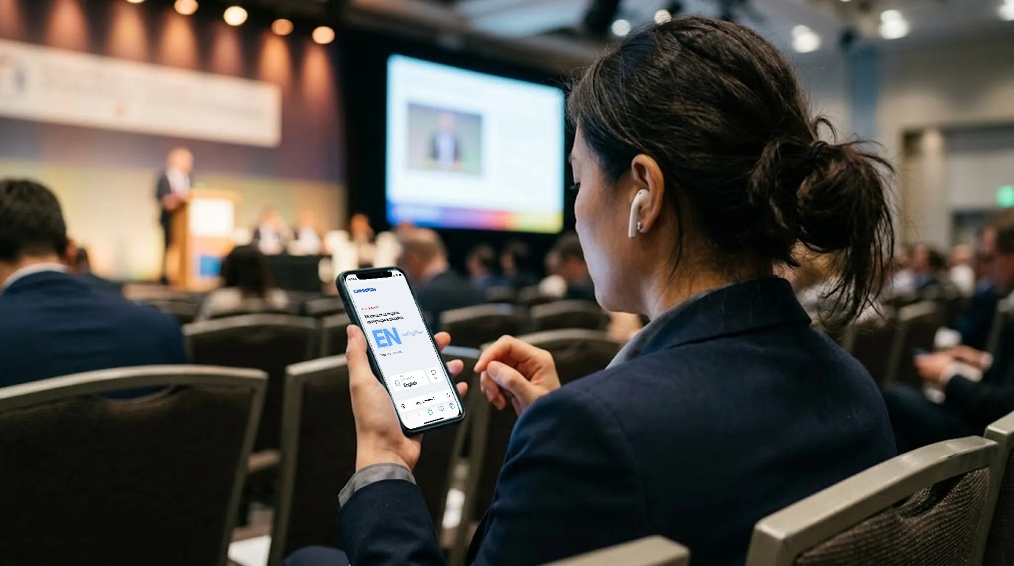 A delegate in the hall listens to the interpretation on her phone